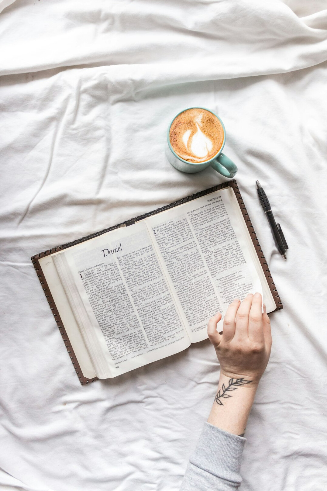 Close-up of hands writing in a journal with a cup of coffee nearby